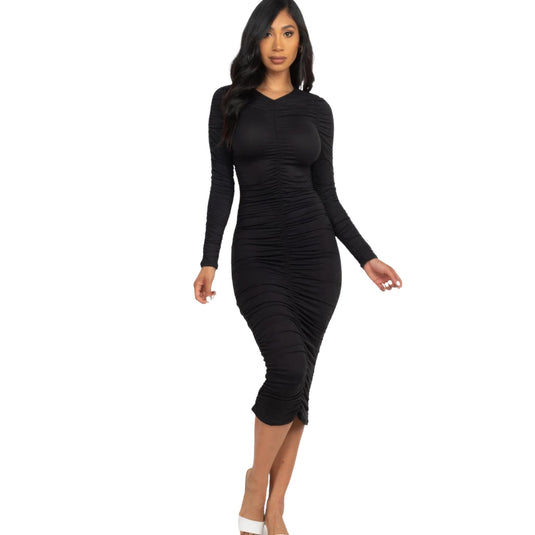 Confident woman in a black ruched long sleeve midi dress with a figure-hugging silhouette, walking in white heels.