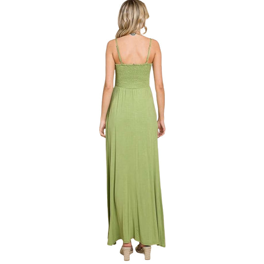Back view of a woman wearing a light green maxi dress with a smocked bodice and thin straps. The dress features a long, flowing skirt, perfect for casual or semi-formal occasions. The model's hair cascades down her back, highlighting the dress's elegant simplicity.