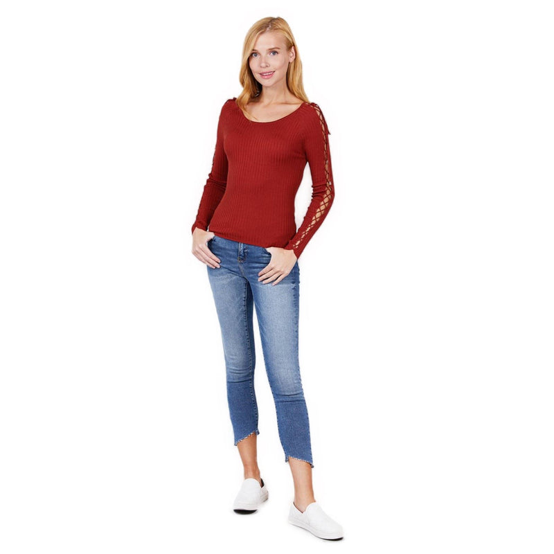 Load image into Gallery viewer, Woman captured in a full-length pose, donning a rust ribbed sweater with strappy sleeves, casual blue denim, and white slip-on shoes.
