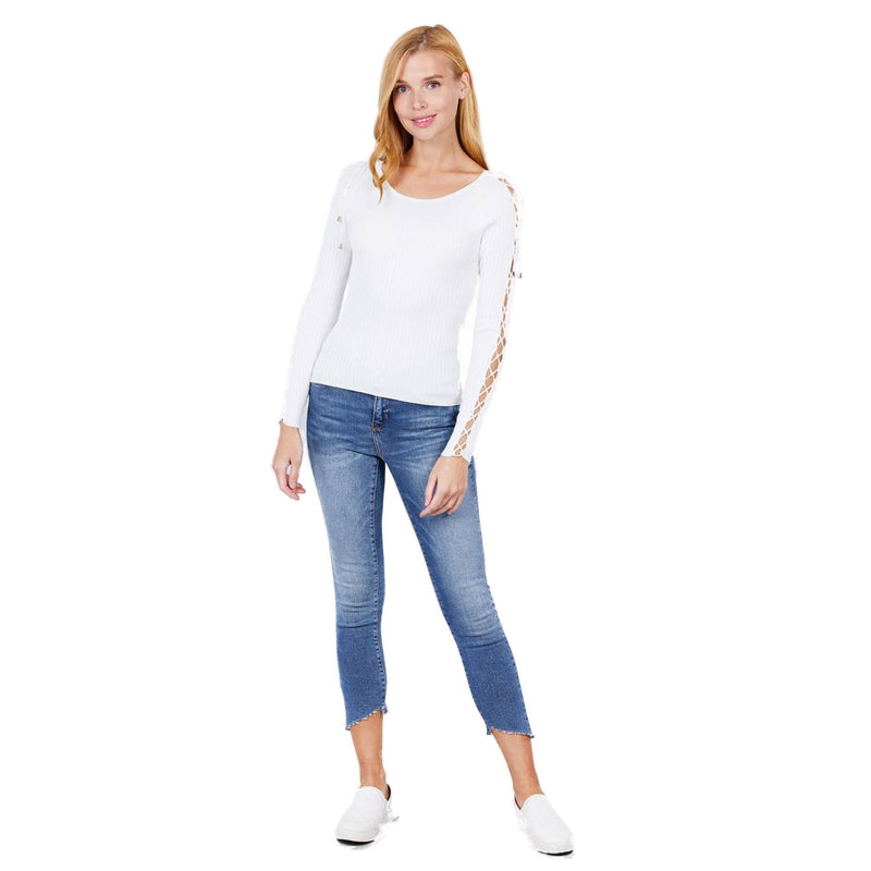 Load image into Gallery viewer, Relaxed yet stylish, a woman poses in a white ribbed sweater with sleeve strappy accents, blue jeans, and white shoes, against a white background.
