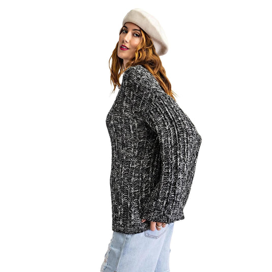 A model poses in a two-tone black and white textured casual sweater, paired with light blue jeans and topped with a stylish beret, against a white background.