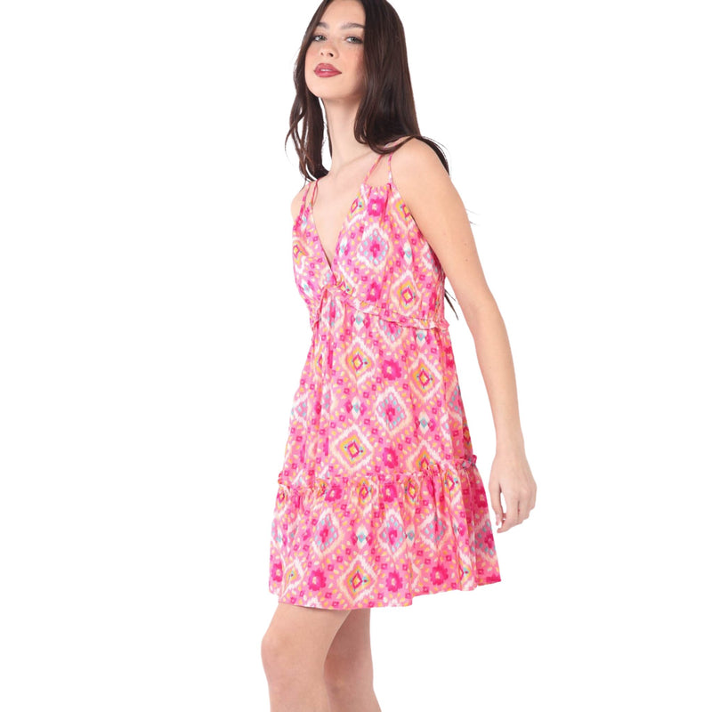 Load image into Gallery viewer, Side view of a young woman in a vibrant multi-color printed mini dress with a deep V-neckline and ruffled hem. The dress has thin shoulder straps and an open back, highlighting its stylish and playful look.
