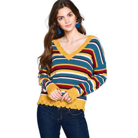 Angled upper body image of a woman sporting a striped V-neck sweater, complemented by blue tassel earrings and a natural, relaxed pose.