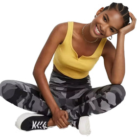 Cheerful woman in a yellow tank top sitting cross-legged, wearing Wild Fable high waist grey camo leggings paired with casual white sneakers.