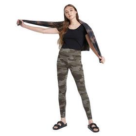A young woman stands extending her arms, wearing Wild Fable ultra-soft high-waisted leggings in a green camo print with a black top and black sandals.