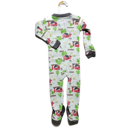 Organic cotton footed pajama for boys featuring a barnyard scene with red barns, green trees, and farm animals, displayed on a hanger against a white background.