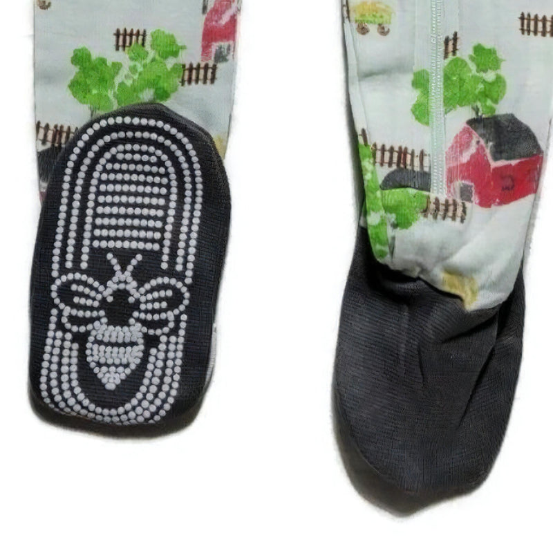 Load image into Gallery viewer, Detail of the non-slip bee-patterned footies on boys&#39; organic cotton pajama, illustrating the safety features and the barnyard print.
